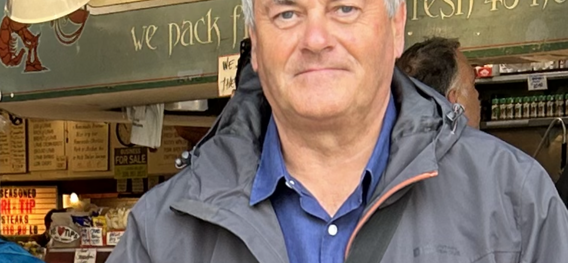 photo of a man standing in front of a shop.