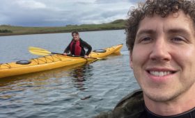 portrait of a man on the right side and woman in a yellow kayak on the left side
